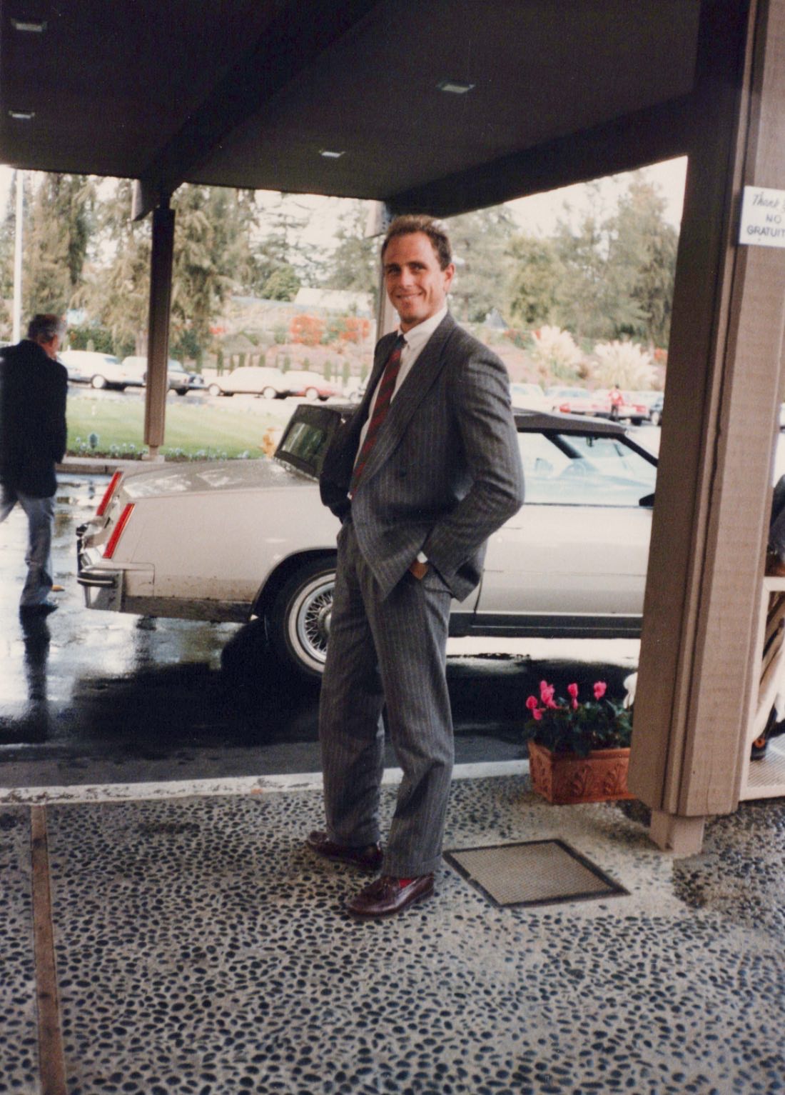 Judd Abrams in a pinstripe suit under a hotel portico